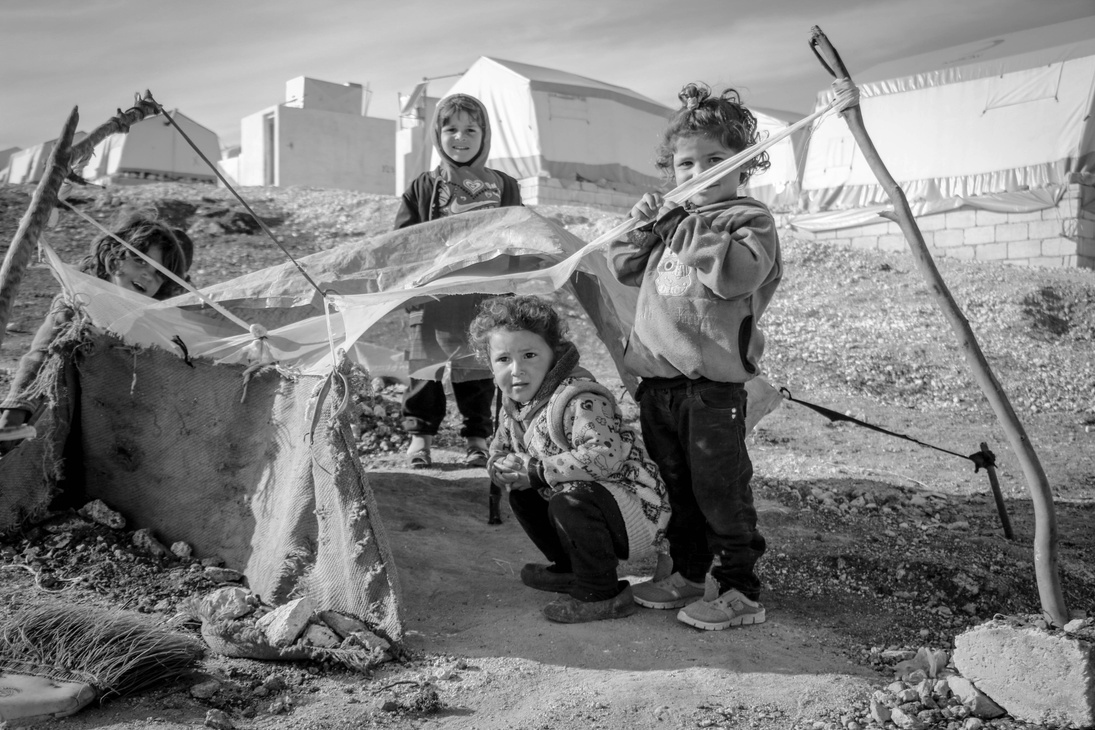a black and white photo of three children standing in front of a tent