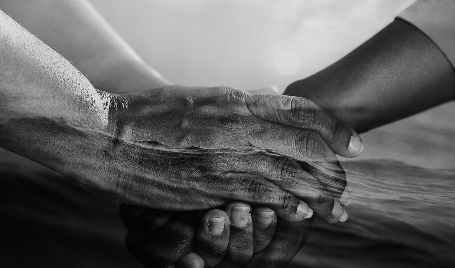 a black and white photo of two hands holding each other